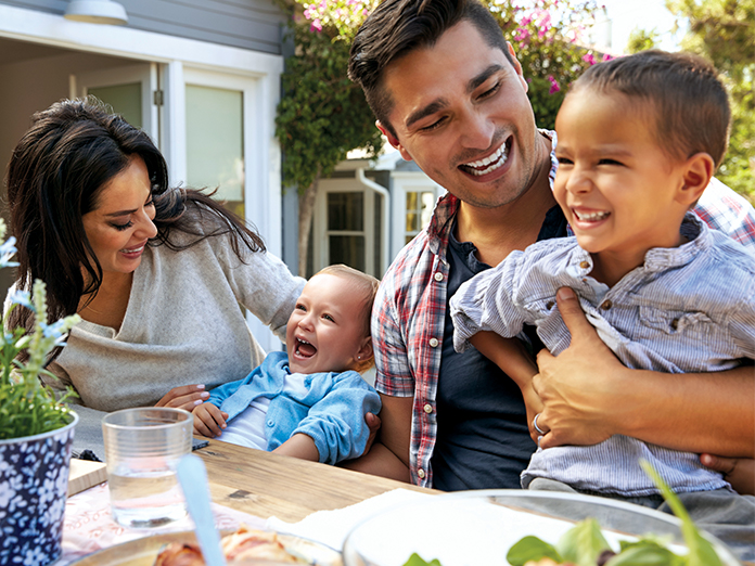 A family eating and laughing outdoors at a table