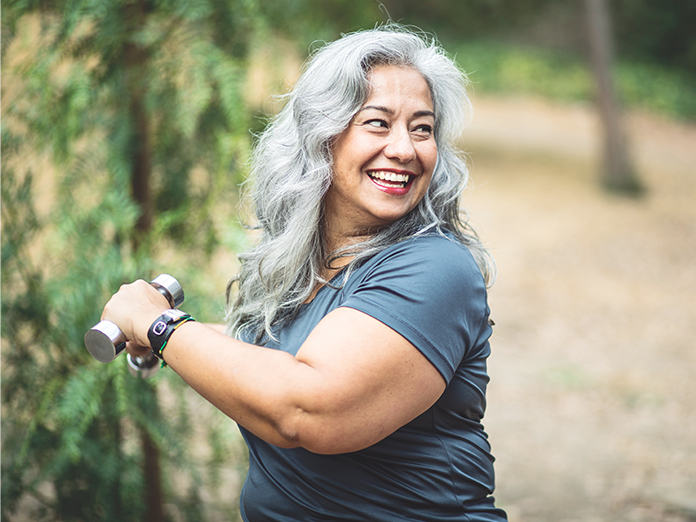 A woman holding small weights and exercising outdoors