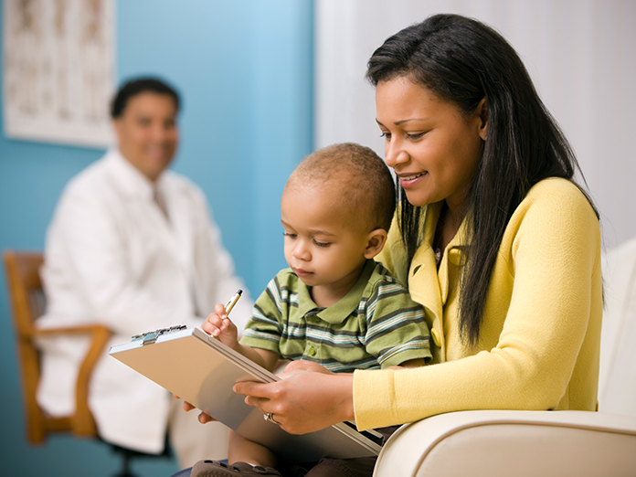 A mother holding her baby at the doctor's office and filling out paperwork