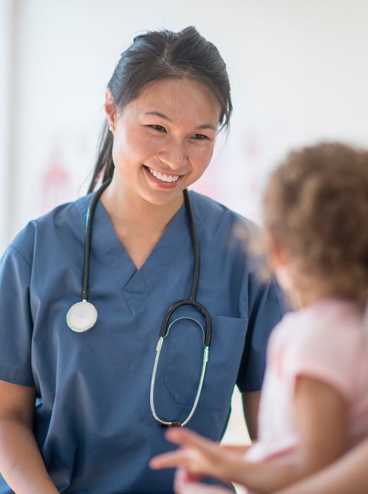A female nurse or doctor smiling at a toddler